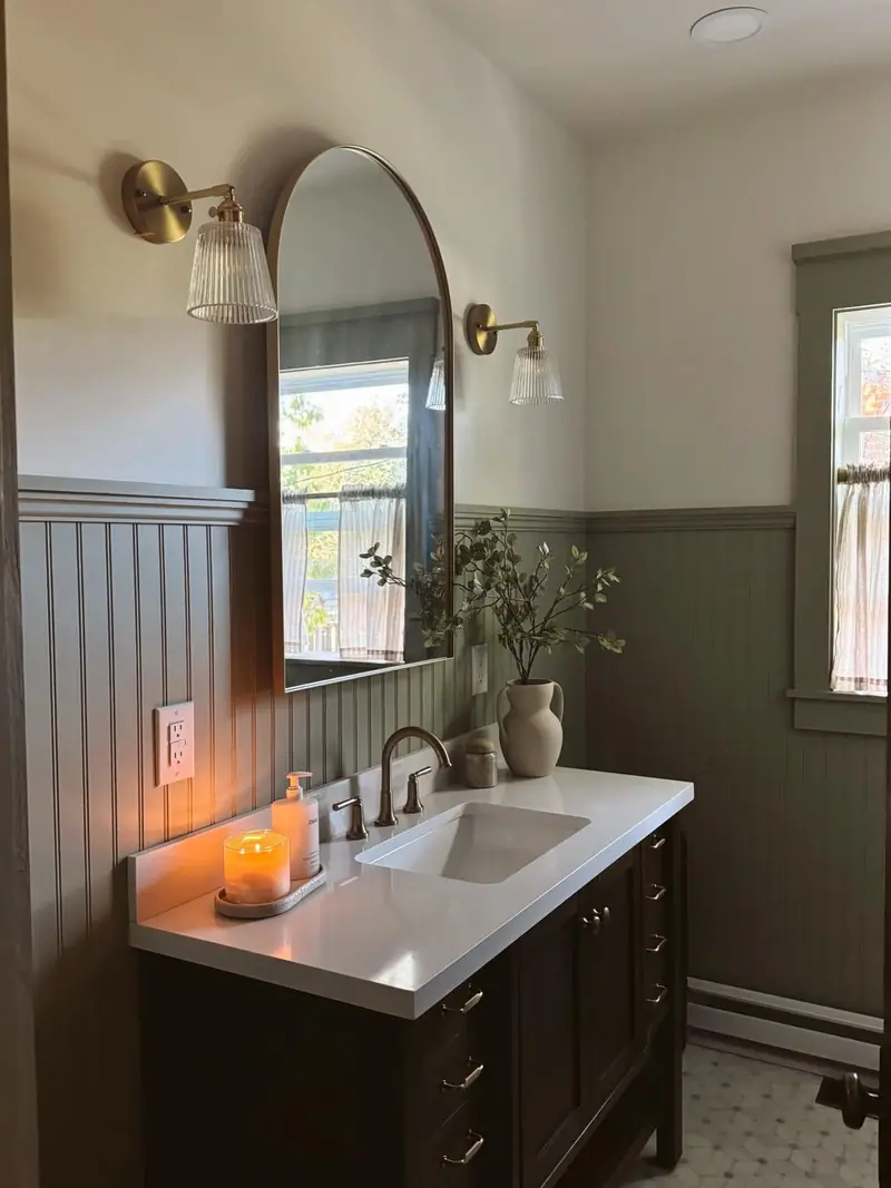 Bathroom remodel in Salisbury, MO: arched brass mirror over a dark wood vanity