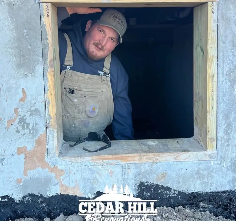 Hunter Creech of Cedar Hill Renovations leaning out of a new basement window opening